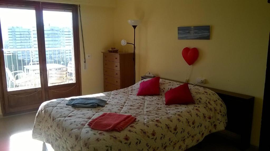 1 dormitorio con 1 cama con almohadas rojas y un corazón en la pared en Apartamento Espert, en El Perelló