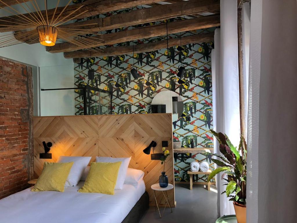 Un dormitorio con una cama blanca y una pared de vidrieras. en 13 suites, en León