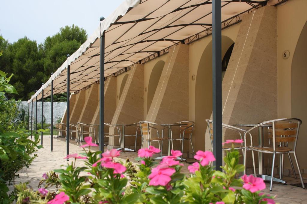 a row of chairs under a tent with pink flowers at Masseria La Porticella in Avetrana