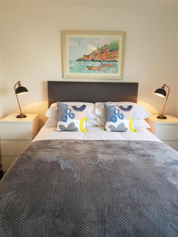 een slaapkamer met een groot bed met 2 lampen bij Carnegie Place in East Kilbride