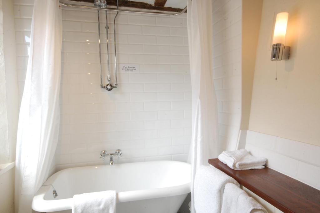 a white bathroom with a tub and a sink at Sutherland House in Southwold