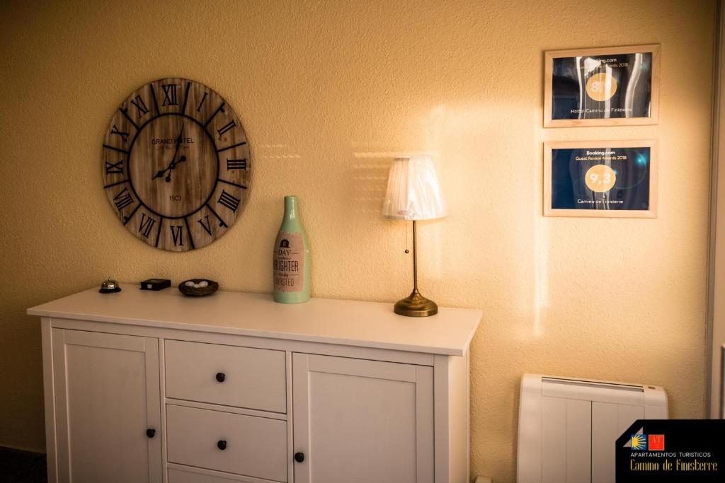 a clock on the wall above a white dresser with a lamp at Camino de Finisterre in Mazaricos