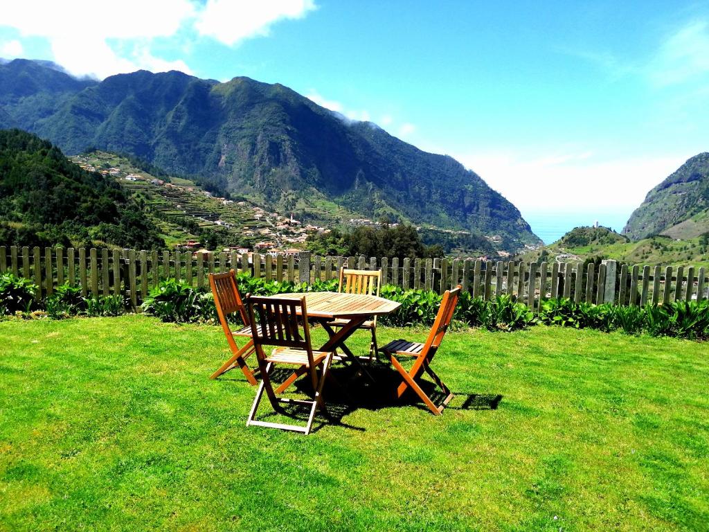 a table and chairs sitting in a yard with mountains at Casa do Vale in São Vicente