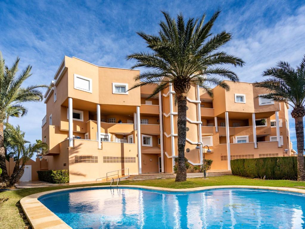 an apartment building with a swimming pool and palm trees at Apartment Sorolla-1 by Interhome in Jávea
