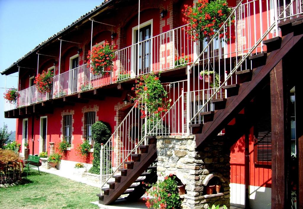 un bâtiment rouge avec des boîtes de fleurs sur les balcons dans l'établissement Bricco Del Gallo, à Sinio
