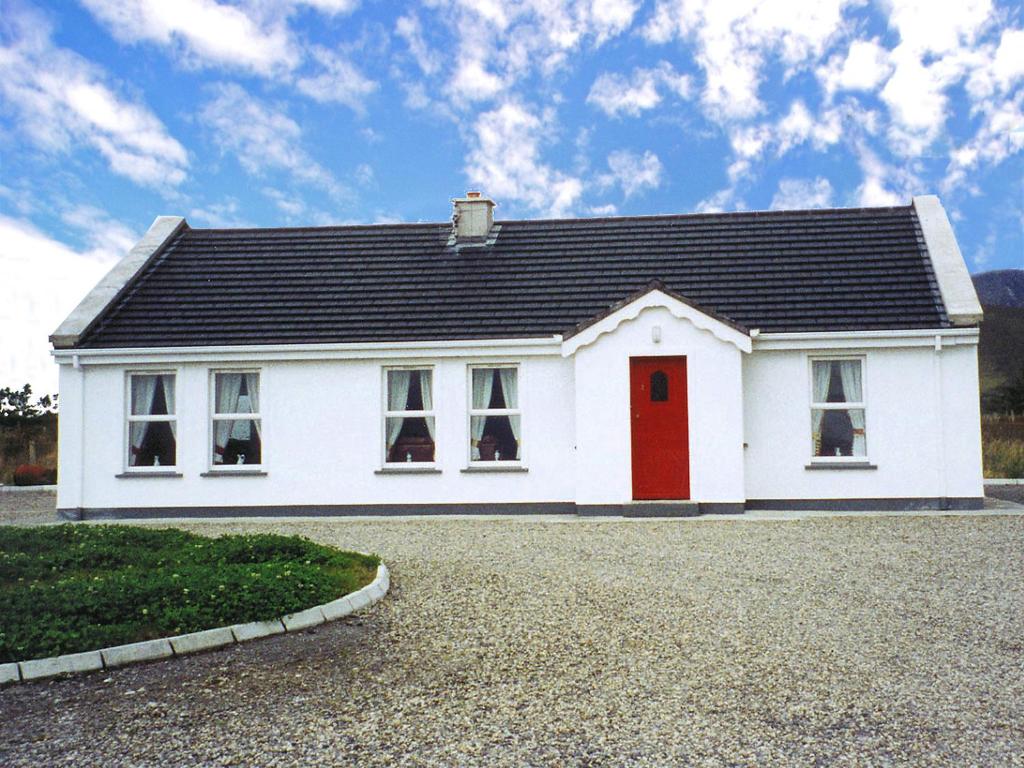 une maison blanche avec une porte rouge dans une allée. dans l'établissement Holiday Home Glenvale Cottage by Interhome, à Valley