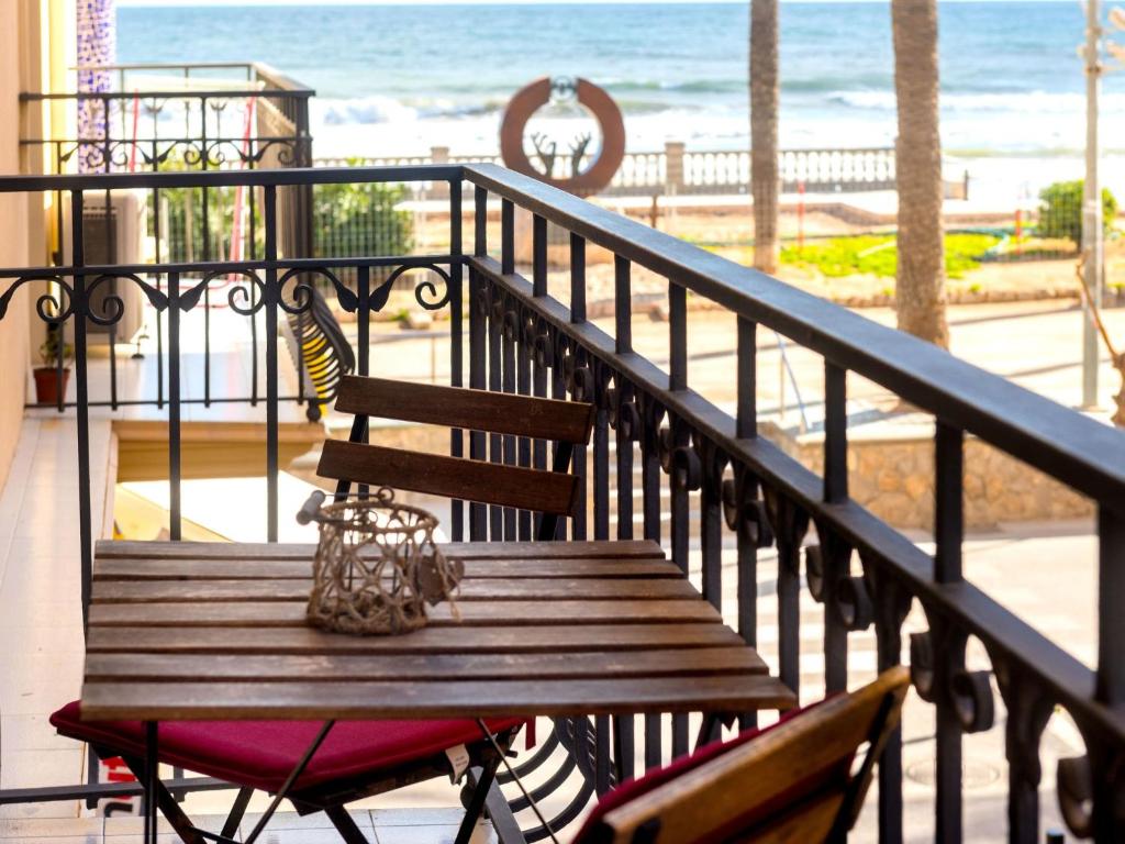 un banco de madera sentado en un balcón con vistas a la playa en Apartment Primer de Maig by Interhome, en Sitges
