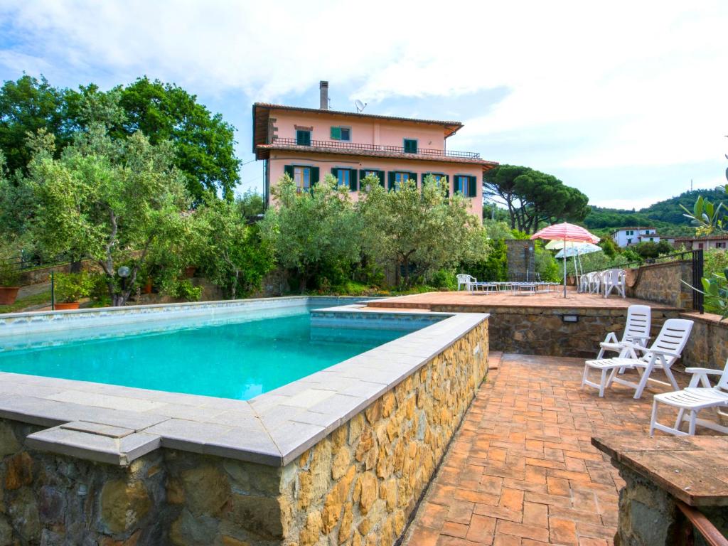 una piscina con una pared de piedra y una casa en Apartment Villa Morosi-2 by Interhome, en San Baronto