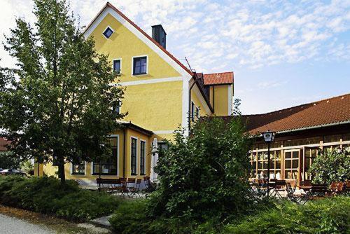 a large yellow house with trees in front of it at Hotel Landgasthof Gschwendtner in Allershausen