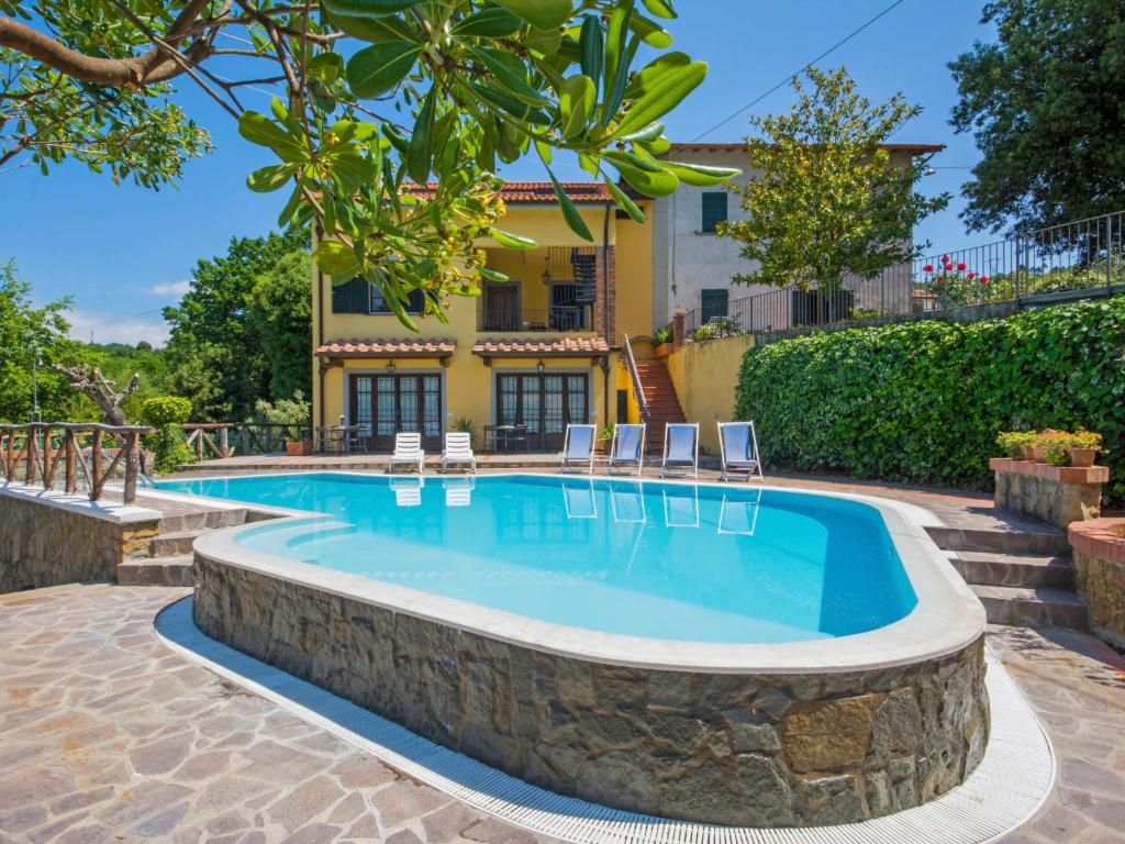 ein Pool mit Stühlen und ein Haus im Hintergrund in der Unterkunft Apartment Poggio alla Baghera-1 by Interhome in Fornello