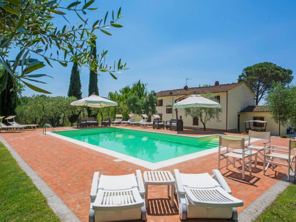a pool with chairs and umbrellas next to a house at Villa Beboli by Interhome in Lamporecchio