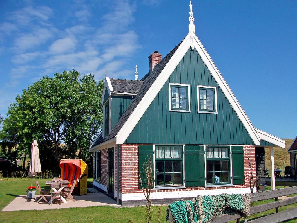 een huis met een groen dak met een tafel en stoelen bij Holiday Home Wiringherlant-7 by Interhome in Noordstroe