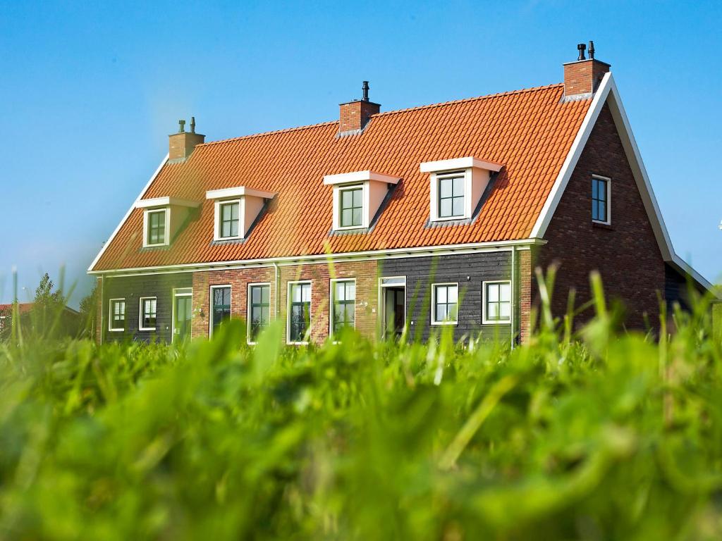 a large house with an orange roof in the grass at Holiday Home Ganuenta-1 by Interhome in Colijnsplaat