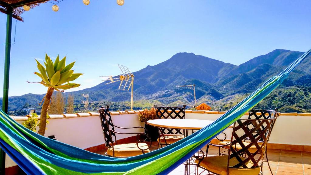 een hangmat op een balkon met een tafel en stoelen bij Apartamento el Parador in Carratraca