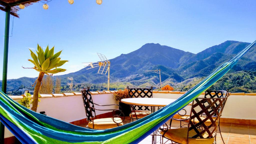 a hammock on a balcony with a table and chairs at Apartamento el Parador in Carratraca