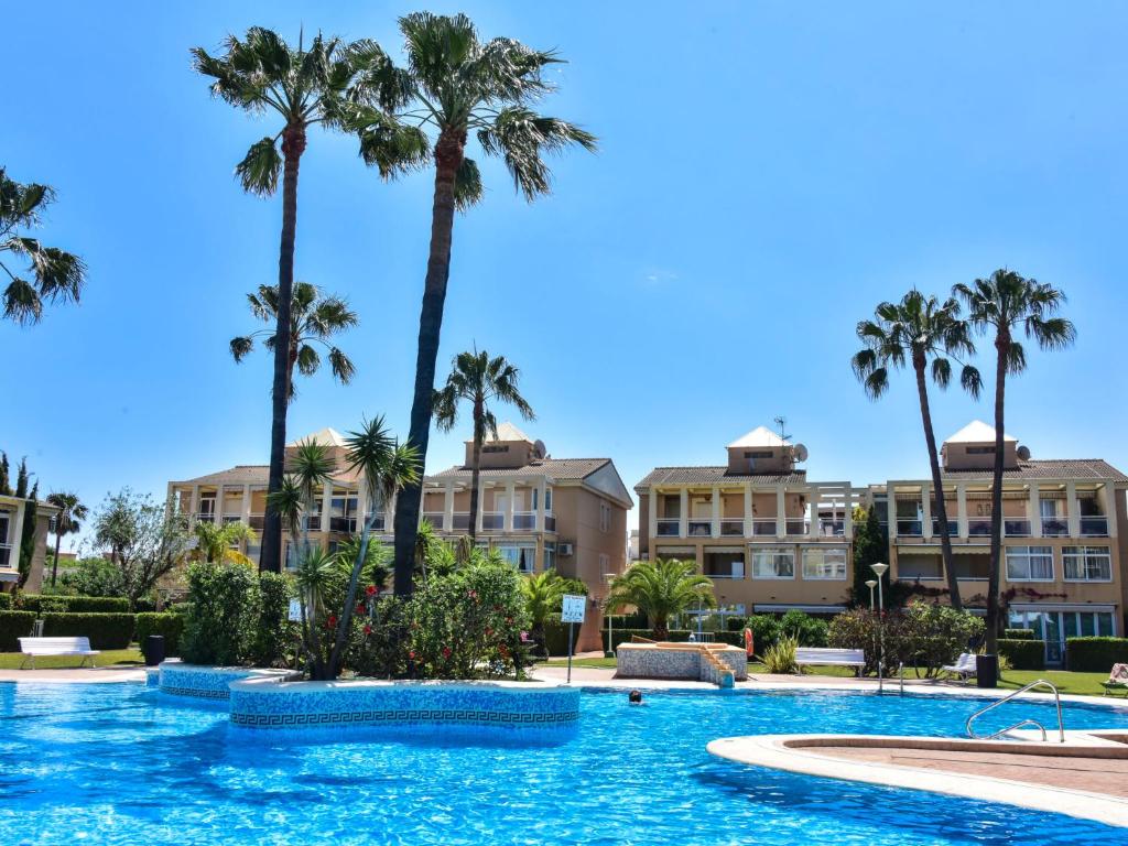 a swimming pool with palm trees in the background at Apartment La Rosaleda-3 by Interhome in Denia