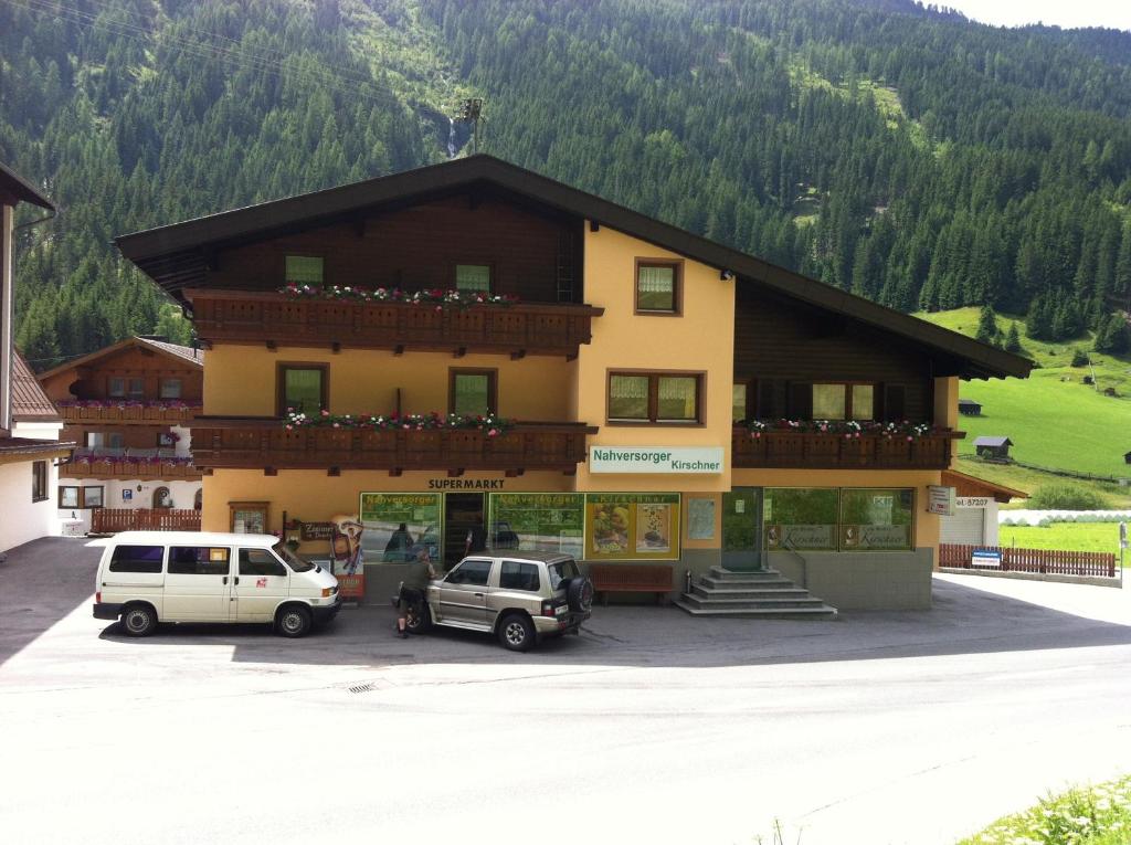 un edificio con dos coches estacionados frente a él en Ferienhaus Bergfrieden, en Sankt Leonhard im Pitztal