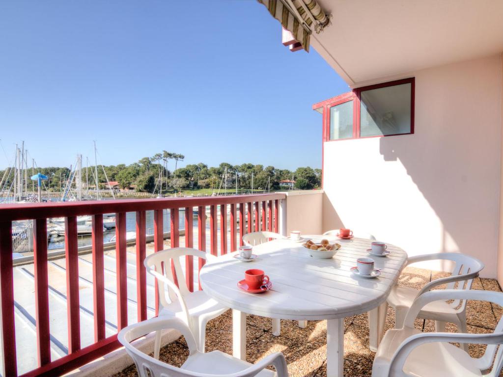 balkon ze stołem, krzesłami i telewizorem w obiekcie Apartment Le Grand Pavois by Interhome w mieście Capbreton