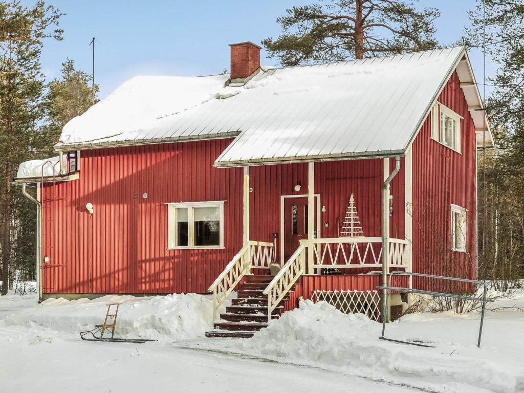 uma casa vermelha com um telhado coberto de neve em Holiday Home Levin mummola by Interhome em Köngäs