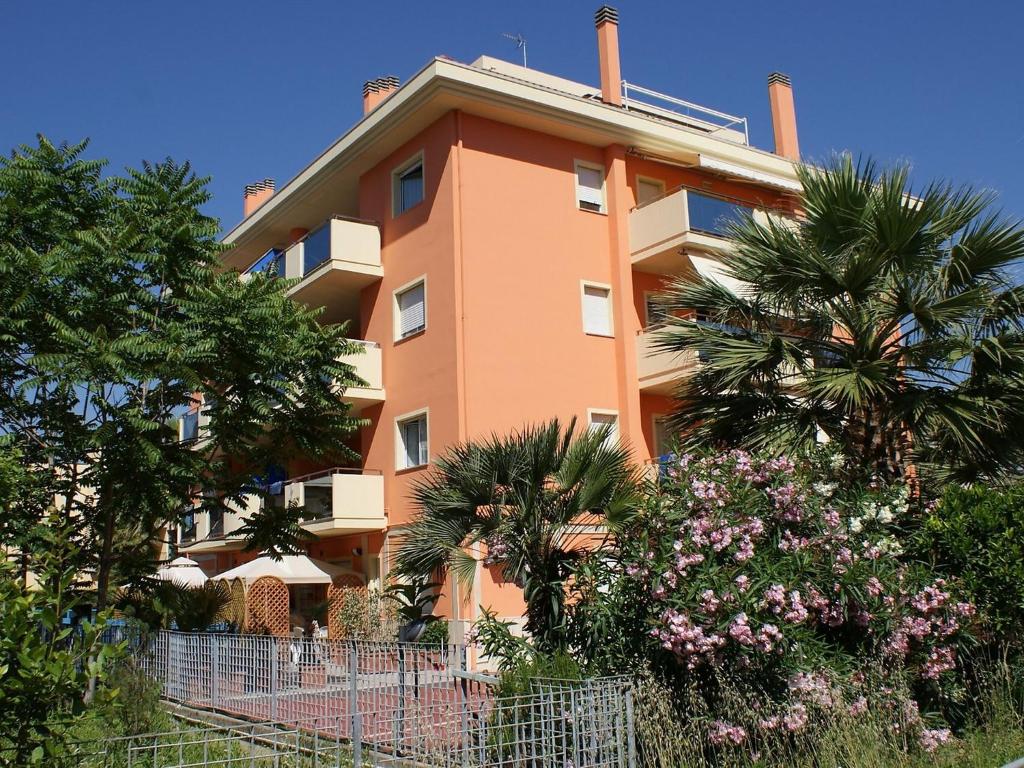 a large orange building with palm trees and flowers at Apartment Azzurra by Interhome in Porto dʼAscoli