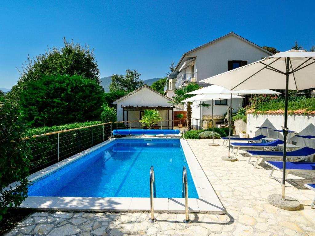 a pool with chairs and an umbrella next to a house at Holiday Home Lucija by Interhome in Matulji