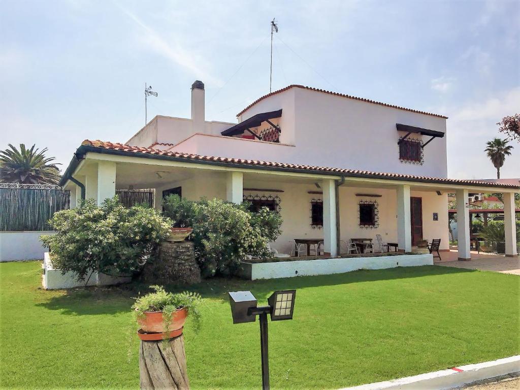 una grande casa bianca con un cortile verde di Holiday Home Fiumara by Interhome a Margherita di Savoia