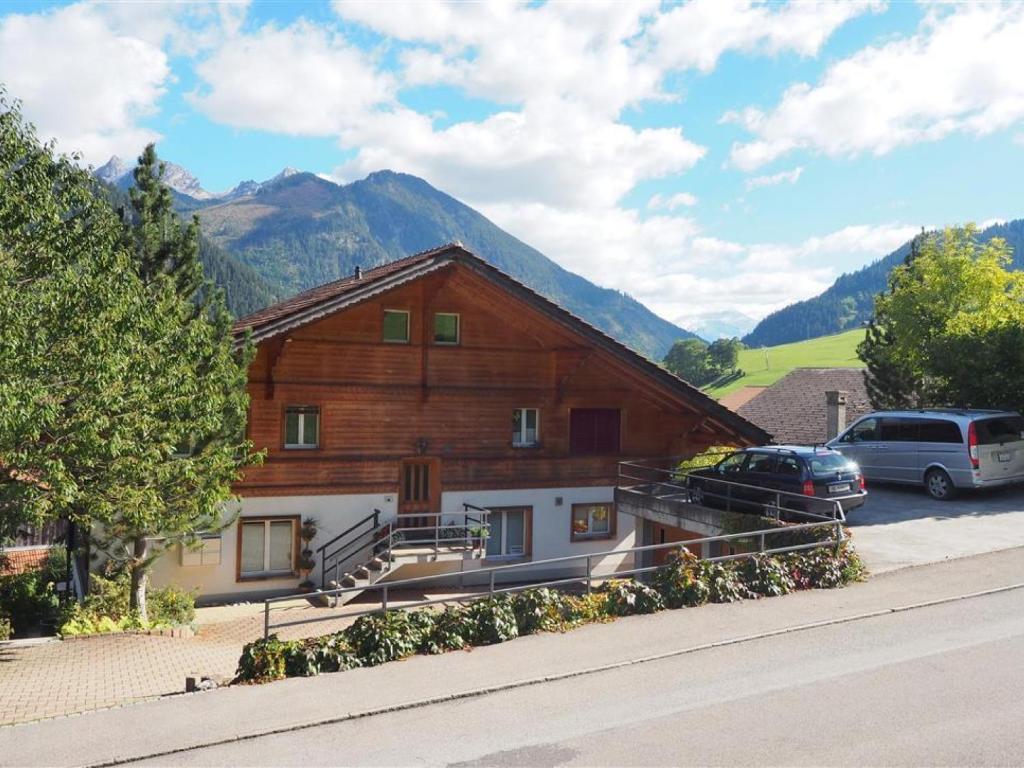 ein großes Holzgebäude mit davor geparkt in der Unterkunft Apartment Am Ryschbächli by Interhome in Zweisimmen