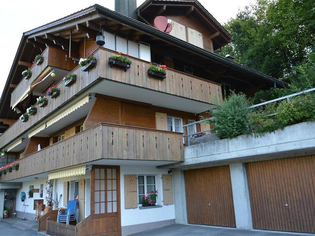 un edificio con balcones de madera y plantas. en Apartment Eichhorn by Interhome, en Zweisimmen