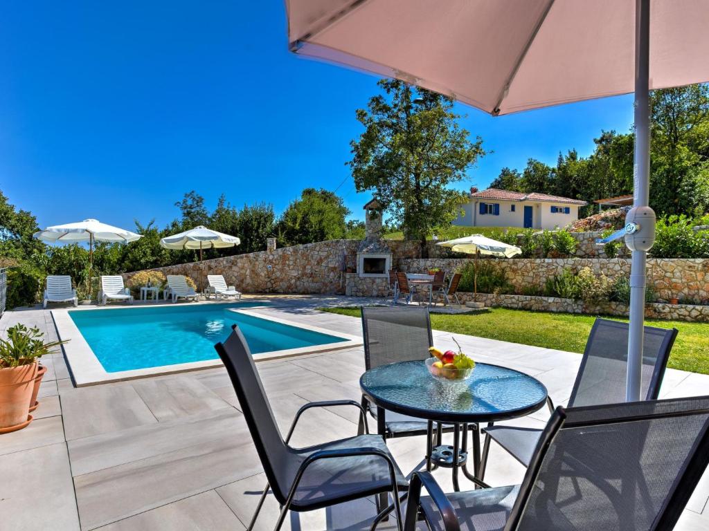 un patio con mesa y sillas y una piscina en Apartment Villa Tara-2 by Interhome, en Brseč
