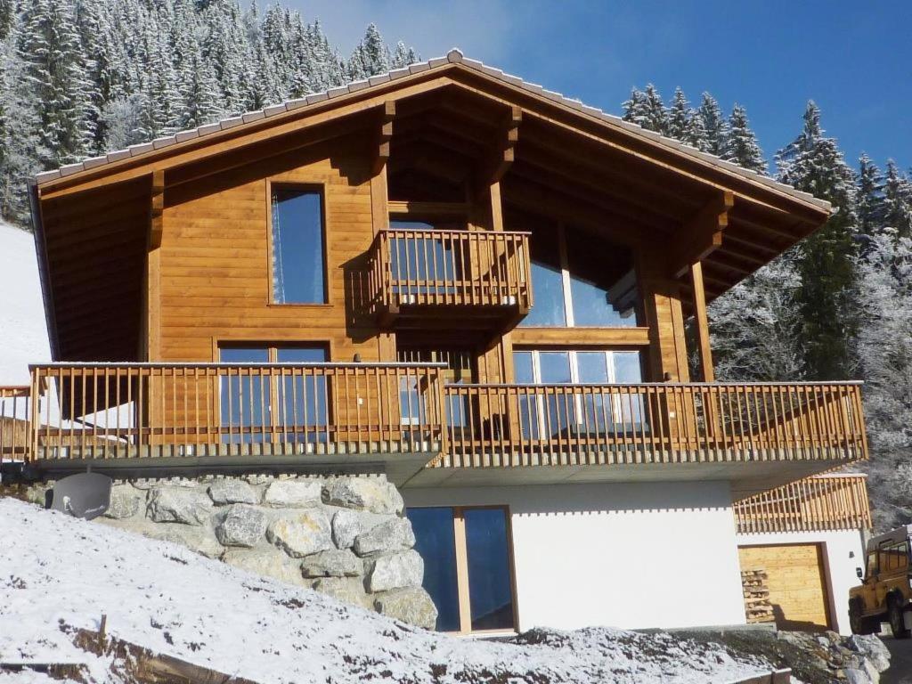 una baita di tronchi nella neve con balcone di Apartment Nubes- Chalet by Interhome a Zweisimmen