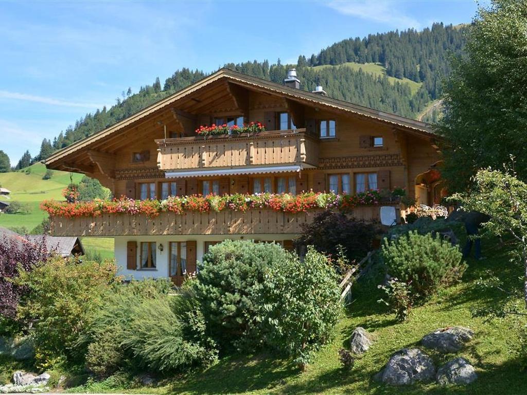 a large wooden house with flowers on the balcony at Apartment Alegria - Parterre by Interhome in Gstaad