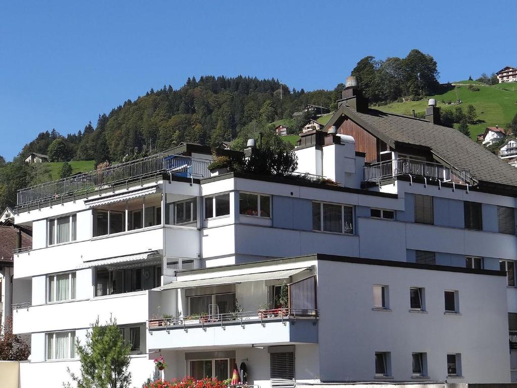 ein weißes Apartmenthaus mit einem Hügel im Hintergrund in der Unterkunft Apartment Dorfstrasse 15 by Interhome in Engelberg