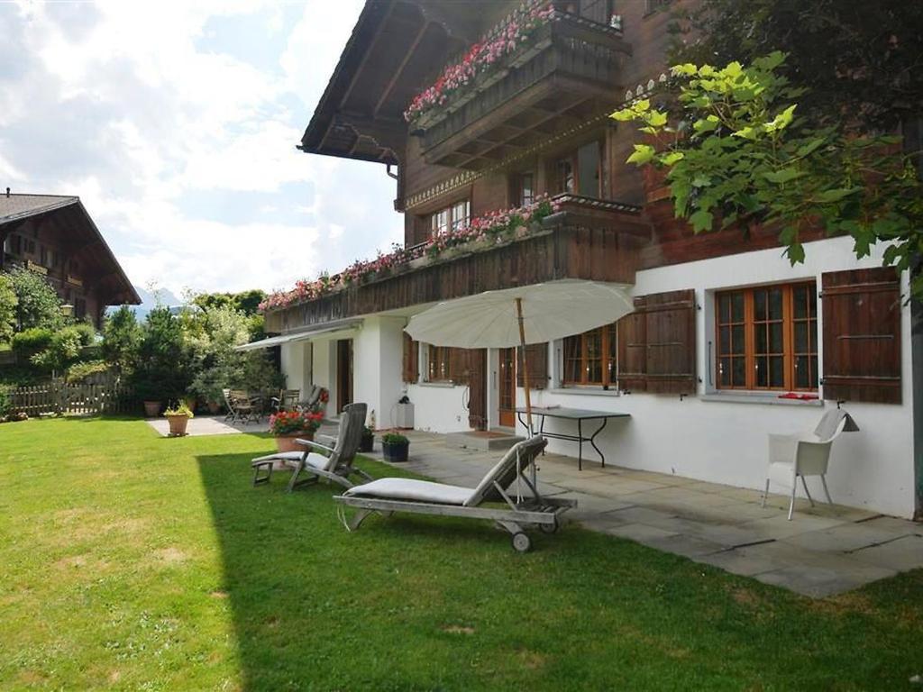 uma casa com um pátio com cadeiras e um guarda-sol em Apartment Sambi by Interhome em Gstaad