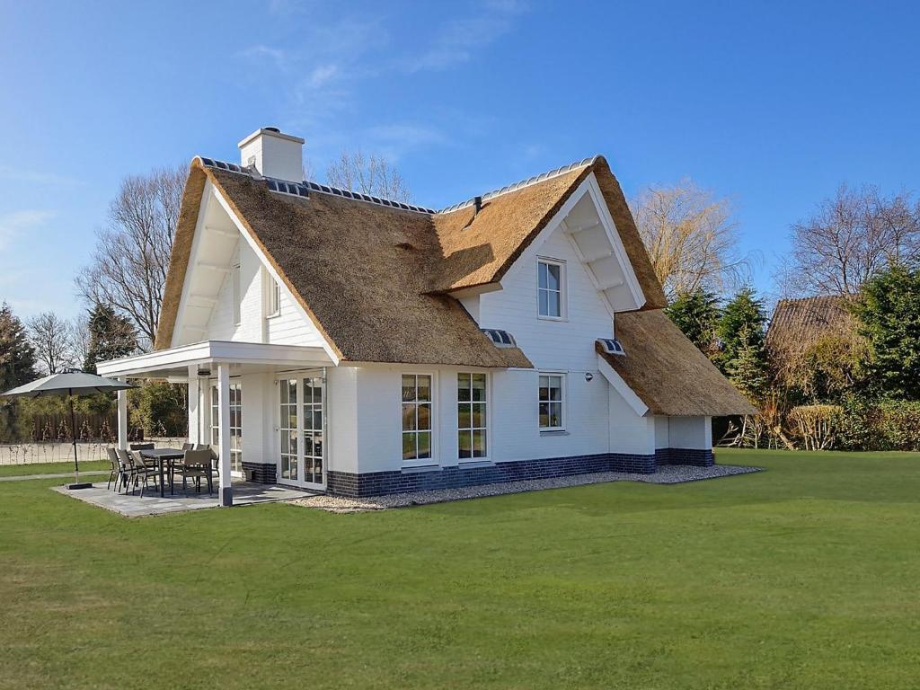 una casa blanca con techo en el césped en Holiday Home de Witte Raaf-1 by Interhome, en Noordwijk