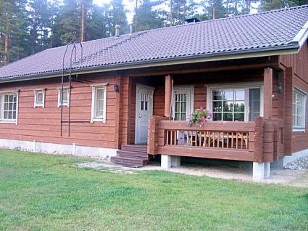 een klein houten huis met een veranda en een bank bij Holiday Home Honkaharju by Interhome in Petäjävesi