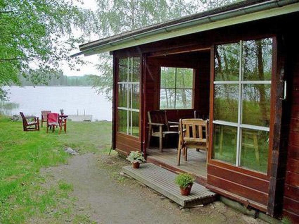 a wooden cabin with a table and chairs in front of a lake at Holiday Home Joutsenlahti by Interhome in Pätiälä
