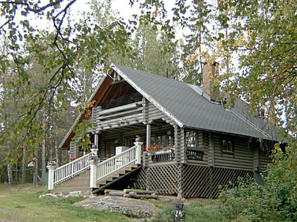 Cabaña de madera con porche y escaleras en el bosque en Holiday Home Villa vuorikotka by Interhome, en Kaivanto