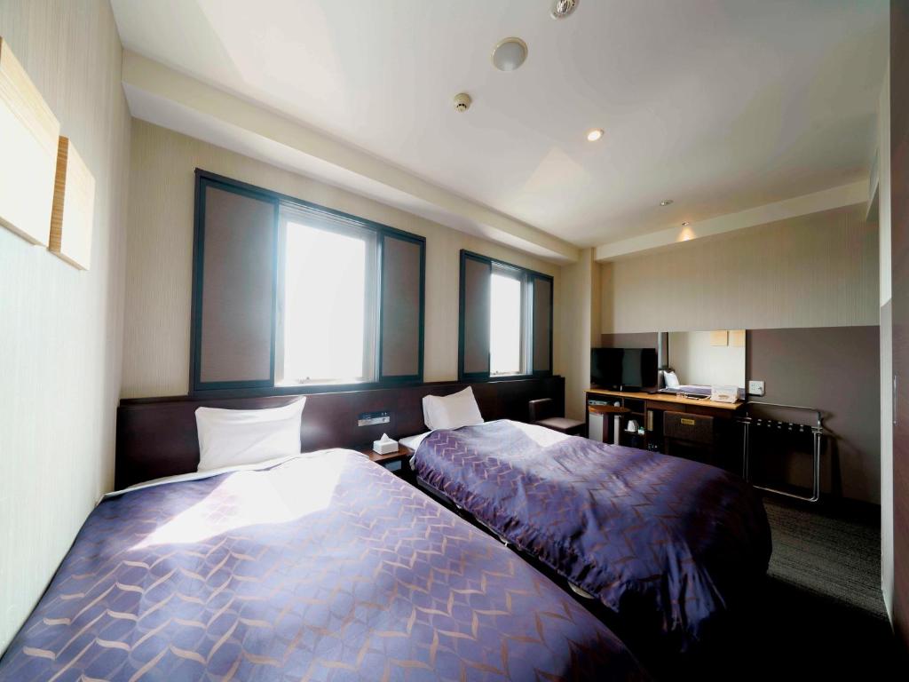 a hotel room with two beds and two windows at Meitetsu Inn Kariya in Kariya