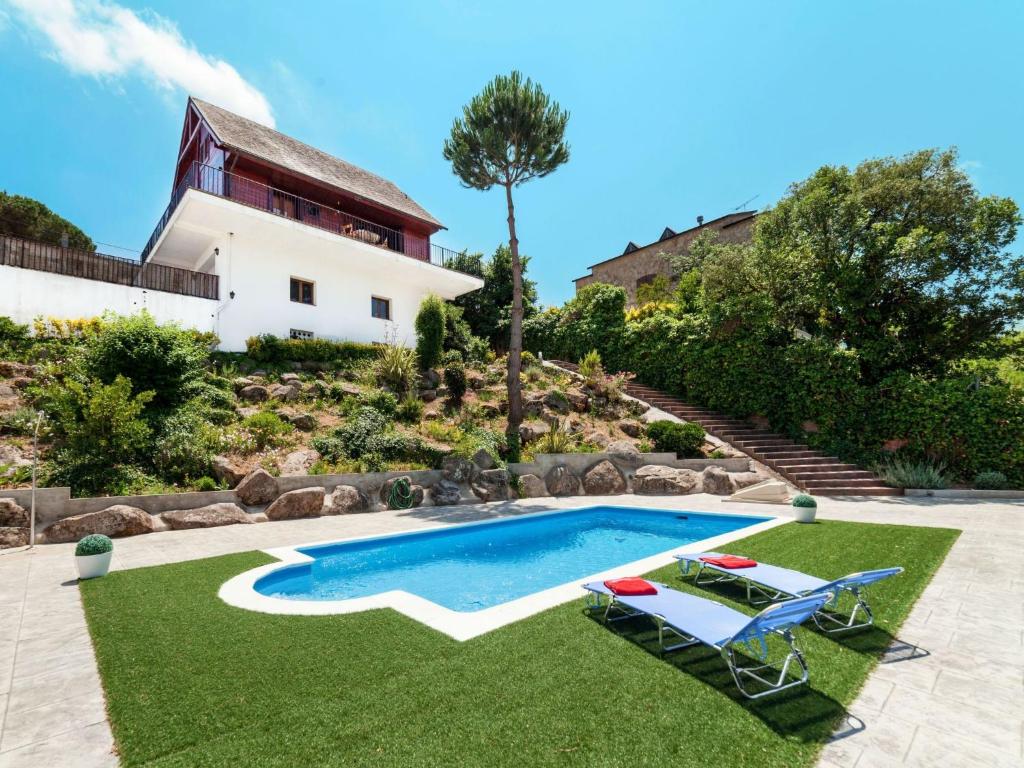 a swimming pool with two lawn chairs and a house at Holiday Home Irisada by Interhome in Fogás de Tordera