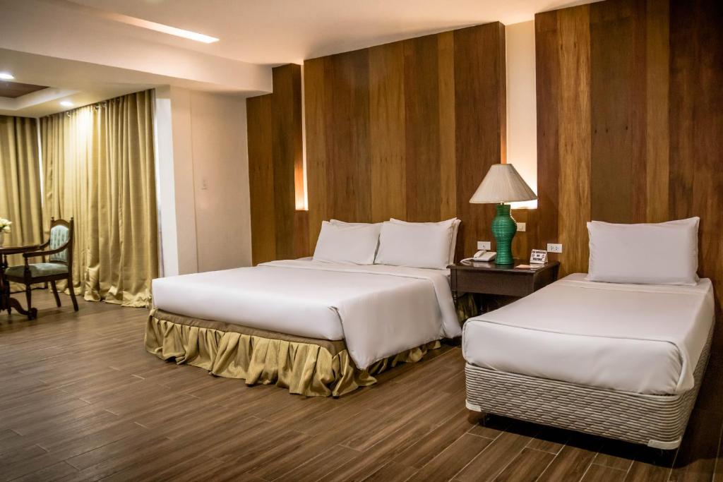 Habitación de hotel con 2 camas y mesa en La Fiesta Hotel, en Iloilo City