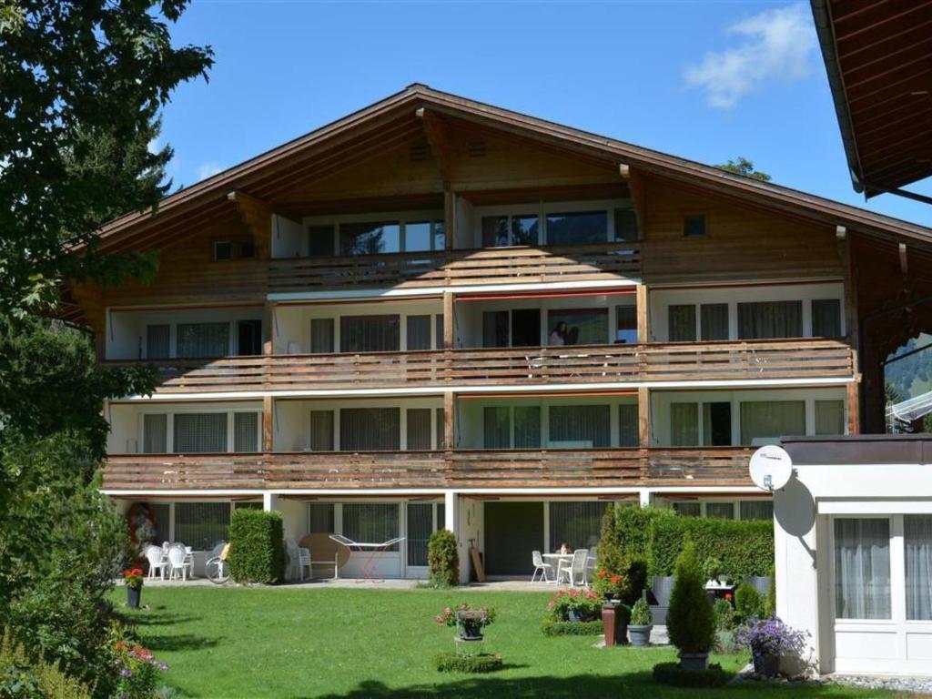 a large wooden house with a lawn in front of it at Apartment La Sarine 212 by Interhome in Gstaad