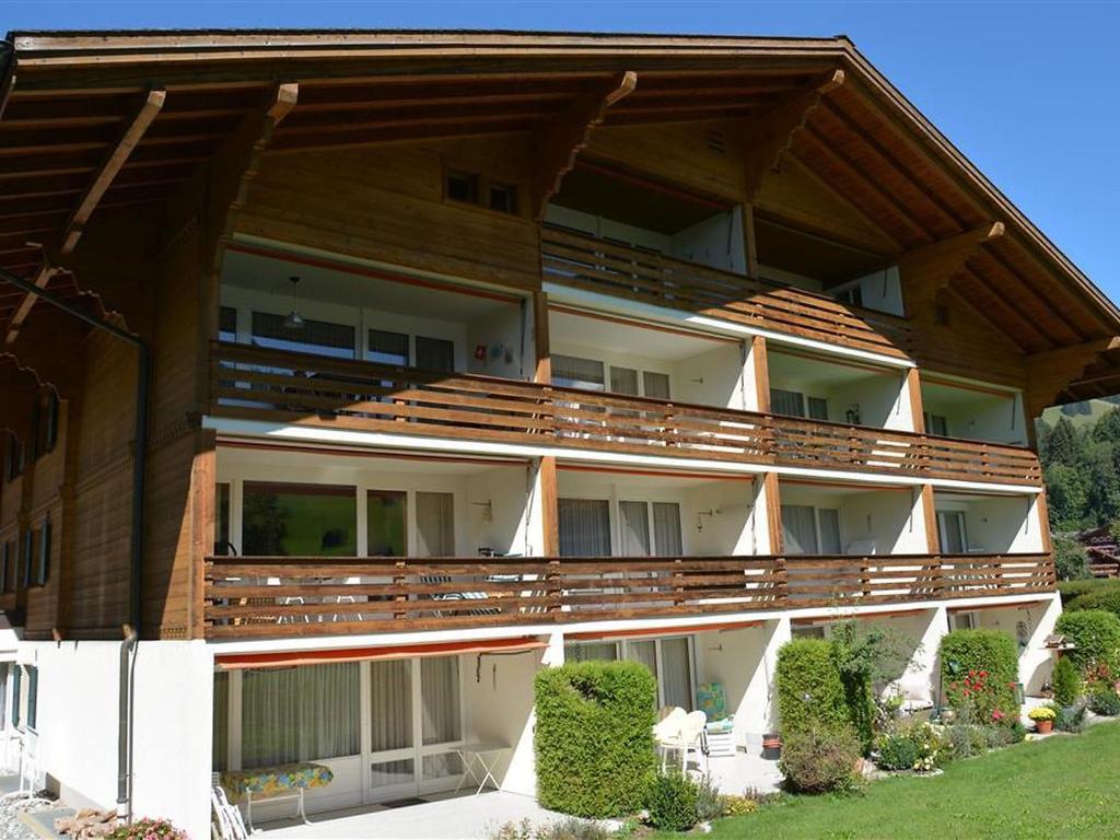 a large apartment building with wooden balconies and bushes at Apartment La Sarine 324 by Interhome in Gstaad