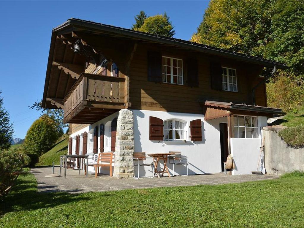 uma casa com uma varanda e uma mesa em frente em Apartment La Ruche- Chalet by Interhome em Gstaad