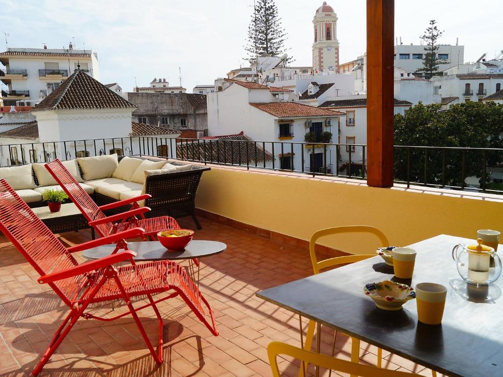 einen Balkon mit roten Stühlen und Tischen auf dem Dach in der Unterkunft Apartment Plaza de las Flores by Interhome in Estepona