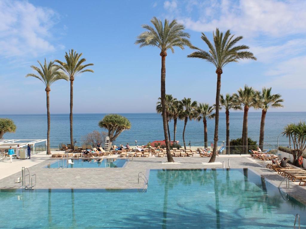 una piscina con palme e l'oceano di Apartment Apartamento O-House by Interhome a Torremolinos