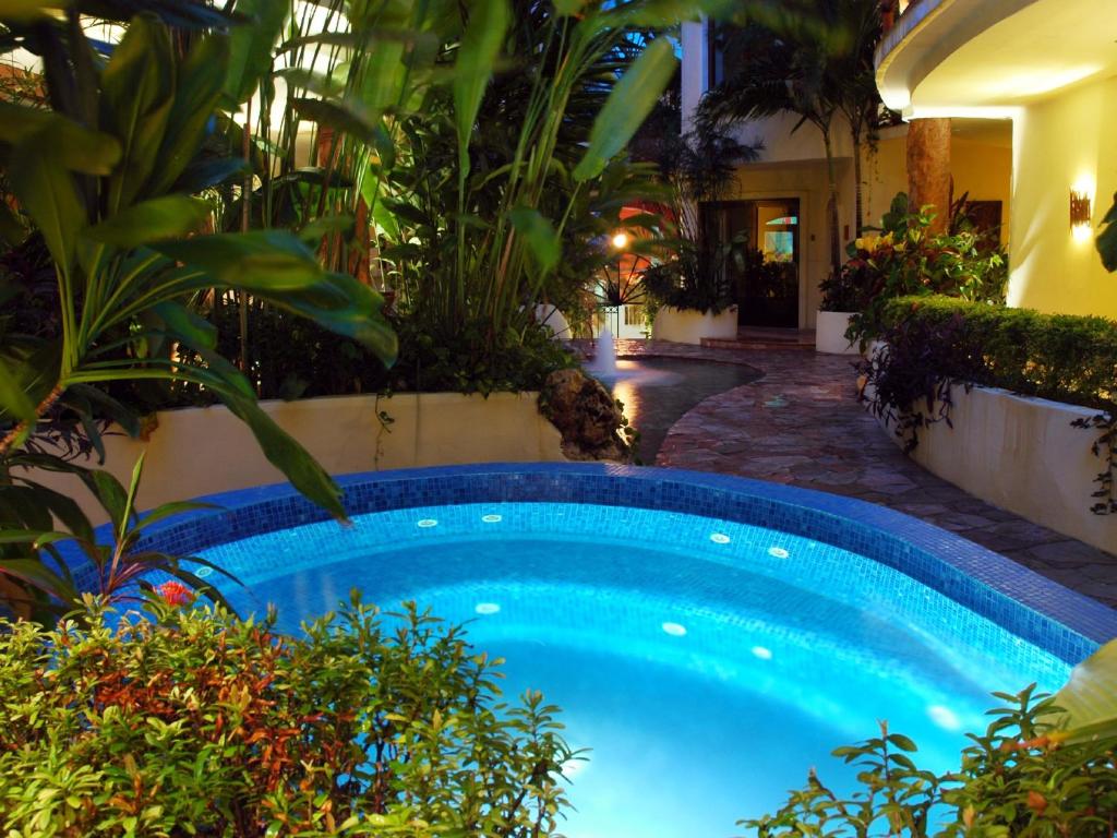 a swimming pool in a garden with plants at Villas Sacbe Condo Hotel and Beach Club in Playa del Carmen