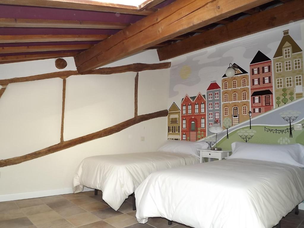 two beds in a room with a mural on the wall at Apartamentos San Francisco 58 in Santo Domingo de la Calzada