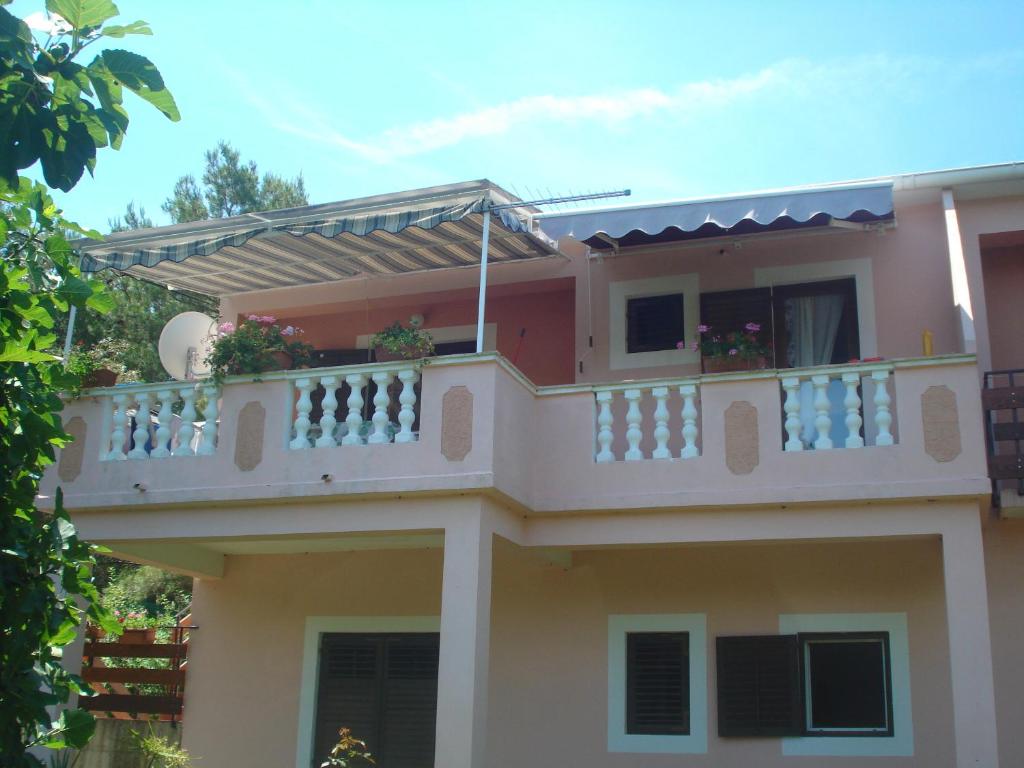 a house with a balcony on top of it at Apartments Vidakovic in Ugljan