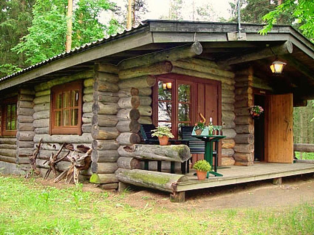 eine kleine Blockhütte mit einer Veranda und einem Tisch in der Unterkunft Holiday Home Metsäpirtti by Interhome in Pätiälä