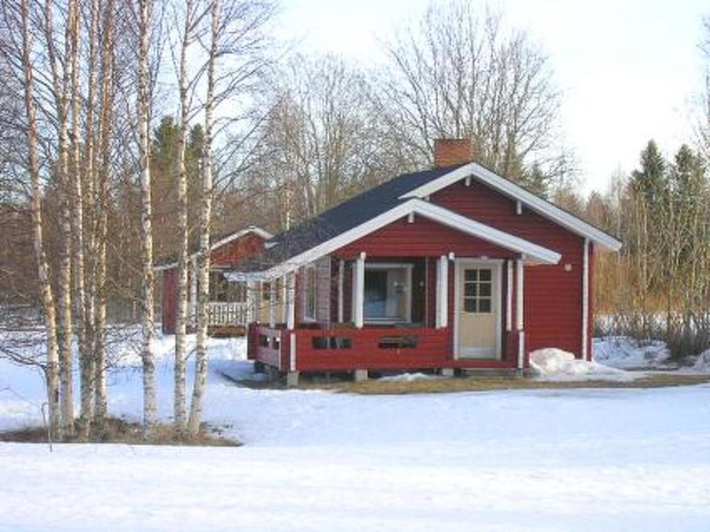 a small red house in the snow with trees at Holiday Home Hilla by Interhome in Jokijärvi